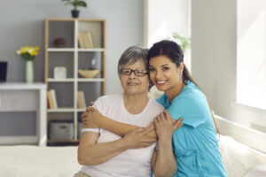Happy Senior Woman Together With Her Home Care Nurse Or Caregive